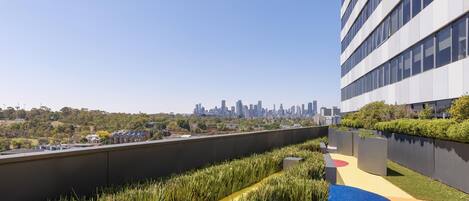 Un jardín en la azotea con un horizonte urbano al fondo.