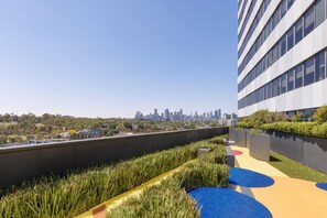 A rooftop garden with a city skyline in the background. - Oaks Melbourne Flemington Suites (Travancore)