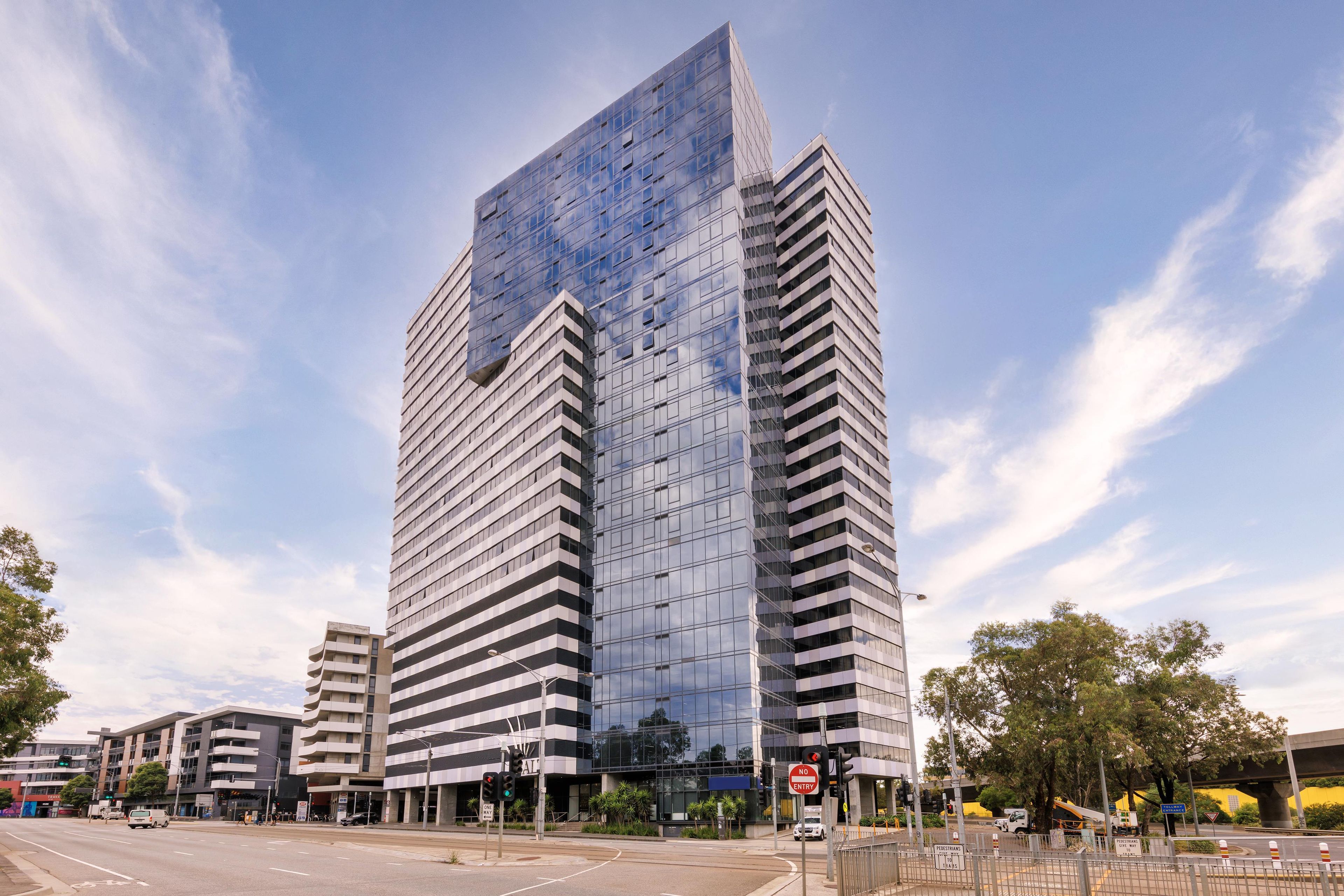 Un edificio moderno de rascacielos con fachada de vidrio, rodeado por un paisaje urbano.