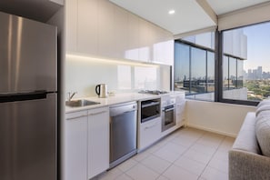 A modern kitchen with stainless steel appliances, a dishwasher, and a gas stove. - Oaks Melbourne Flemington Suites (Travancore)