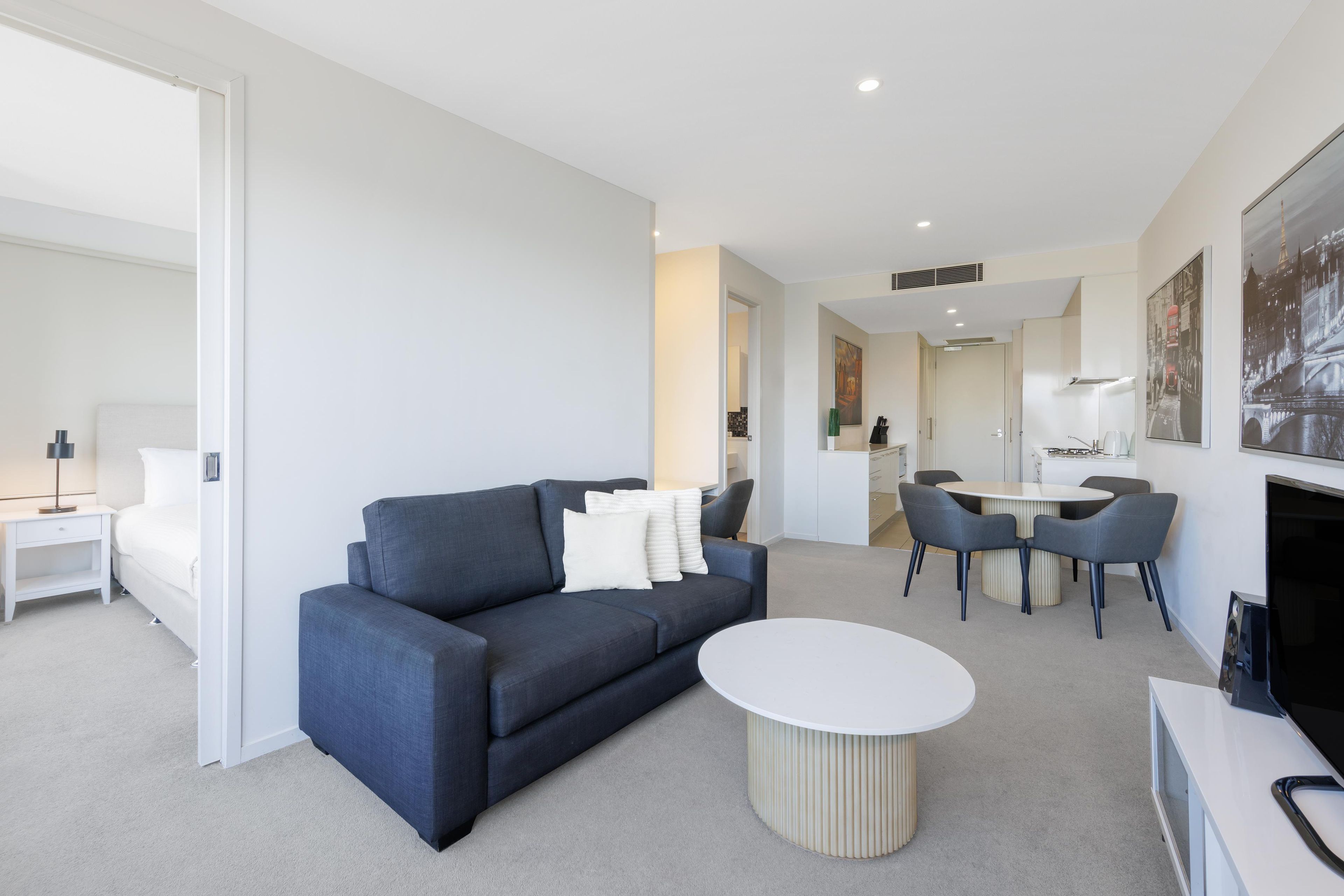 Een moderne woonkamer met een bank, een rond salontafeltje en een eethoek met stoelen en een tafel.