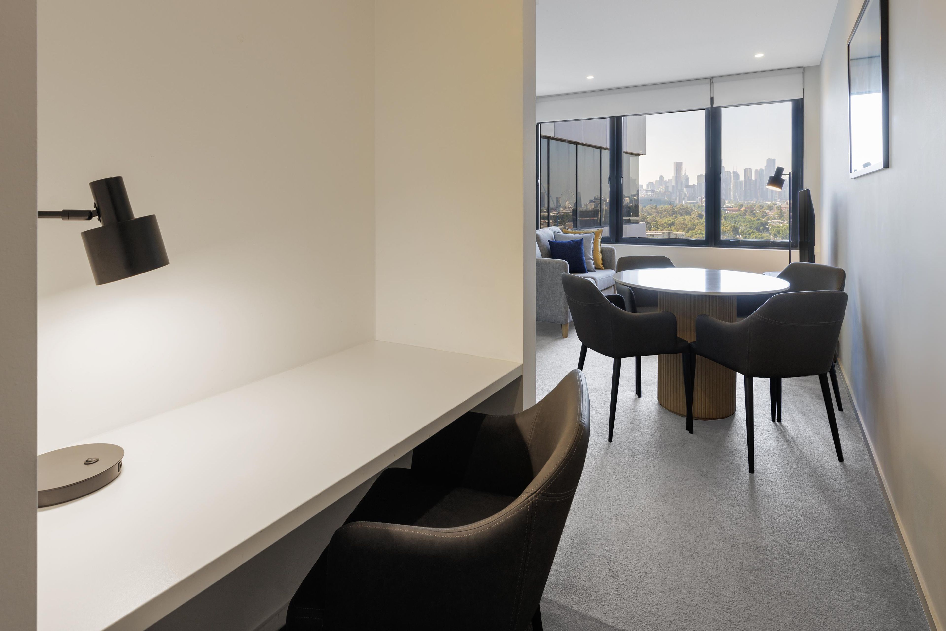 A modern office space with a white desk, a round table, and several chairs.