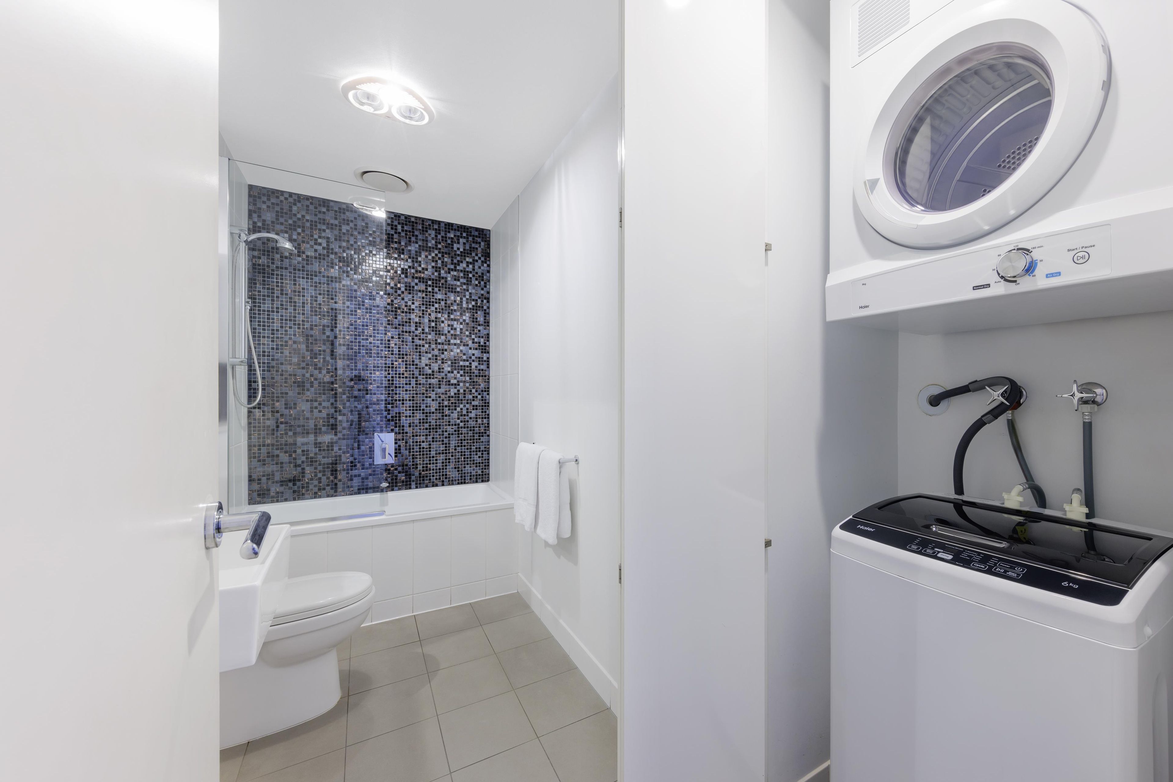 Une salle de bain moderne équipée d’une douche, de toilettes et d’un lave-linge encastré.