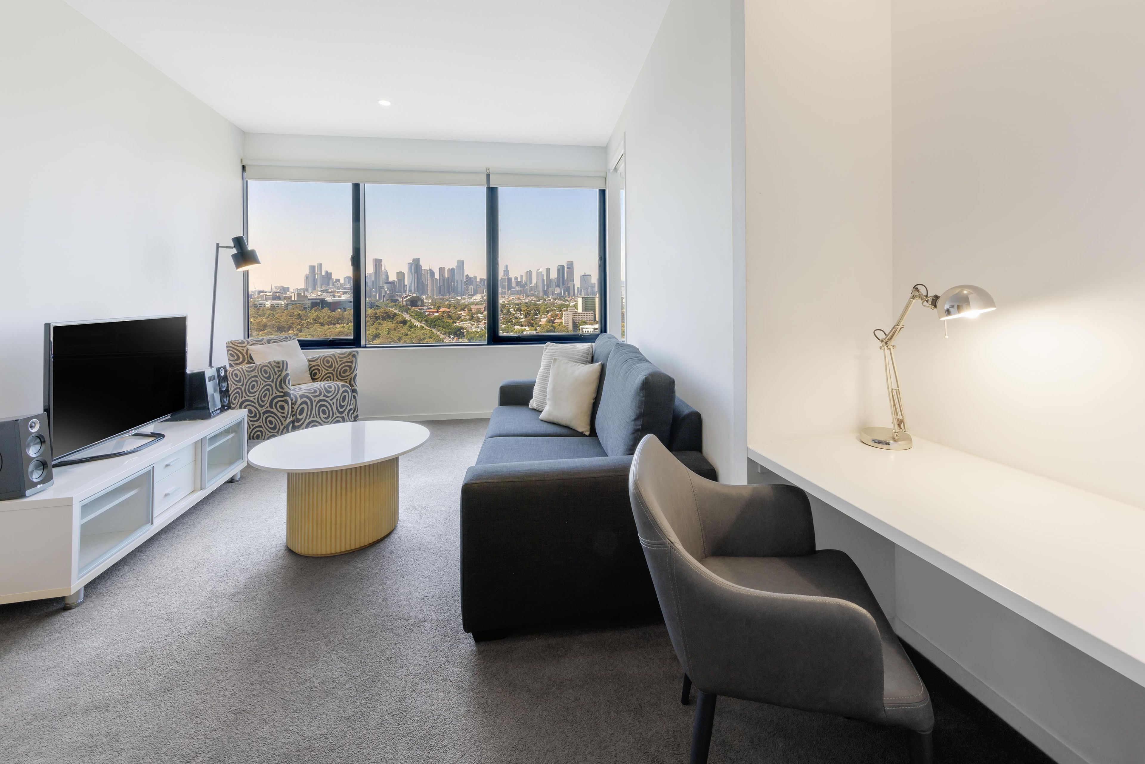 A modern living room with a city view, a flat-screen TV, a coffee table, a sofa, and a side table.