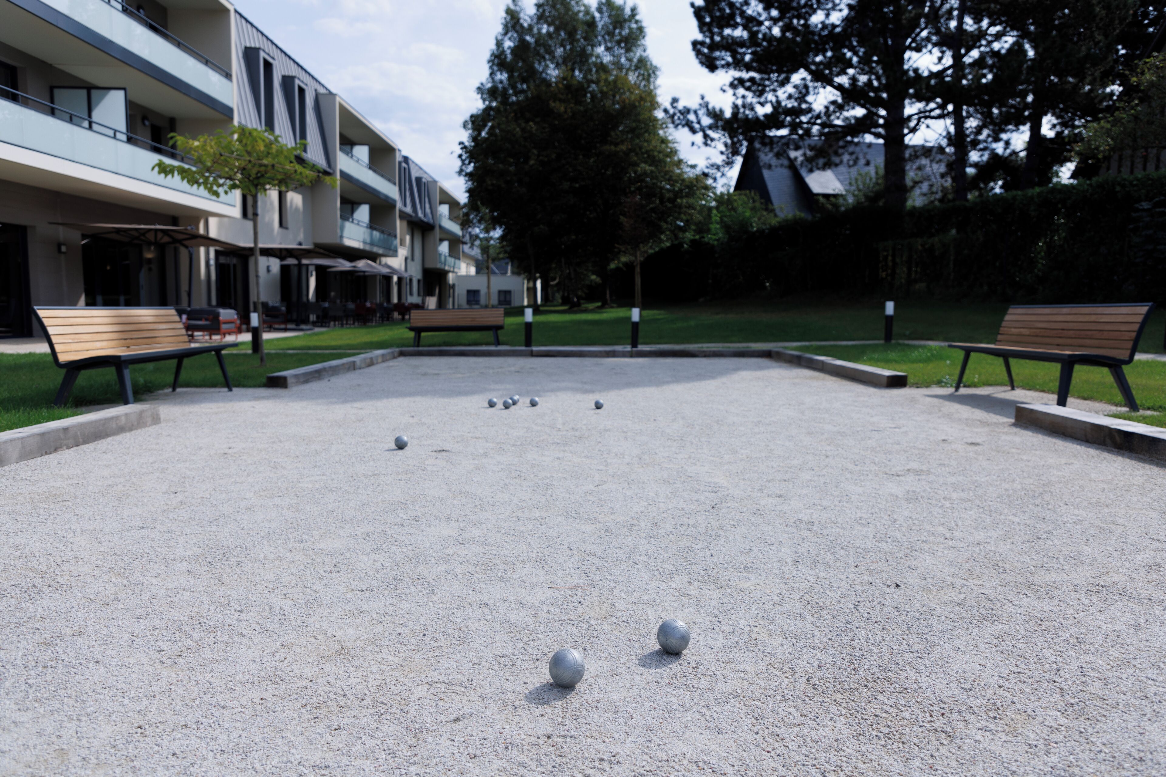 Une cour dallée de gravier, avec des bancs et un bâtiment à plusieurs étages doté de balcons.