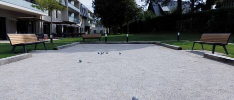 Une cour dallée de gravier, avec des bancs et un bâtiment à plusieurs étages doté de balcons.