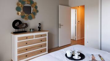 A bedroom with a bed, a dresser, a mirror, and a magazine on the bed.