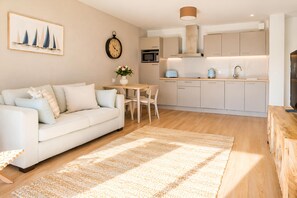 Una sala de estar moderna con un sofá, una mesa de comedor y una cocina con armarios y electrodomésticos.
