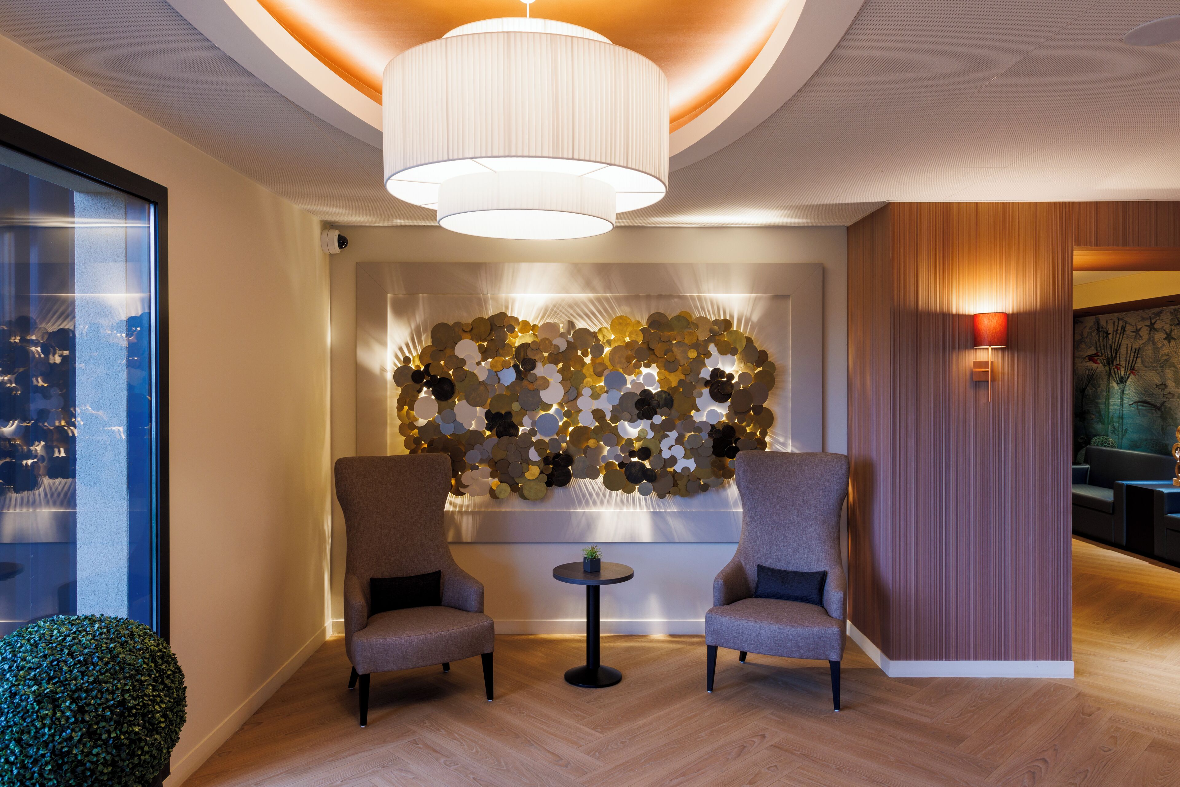 A modern lobby with two armchairs, a round table, and a decorative wall with circular patterns.