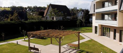 Un patio con una pérgola de madera, una banca y un camino pavimentado.