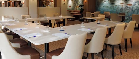 A conference room with long tables, chairs, and a large mural of fish on the wall.