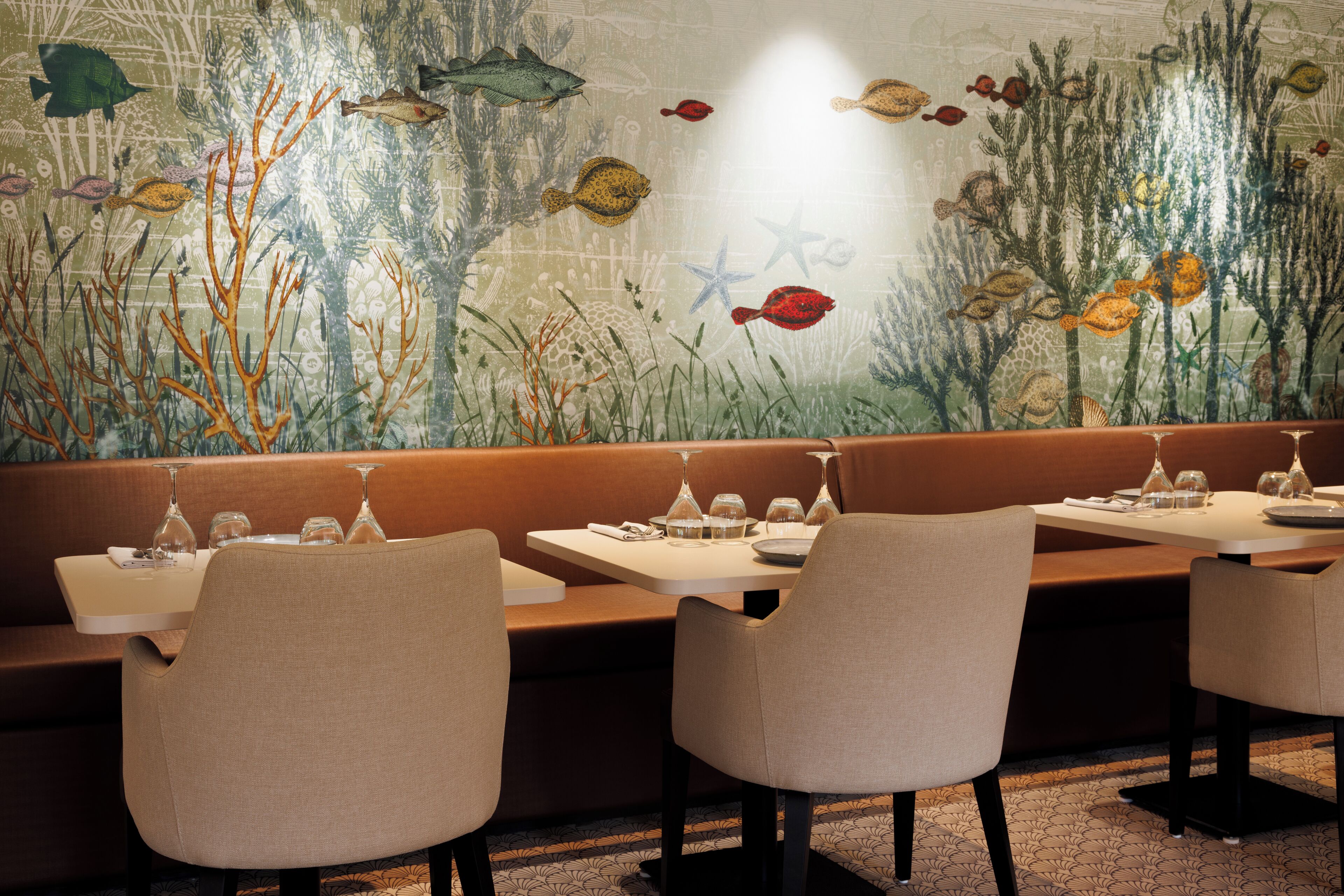 Un restaurante con un mural de una escena submarina, con cabinas y mesas dispuestas para comer.