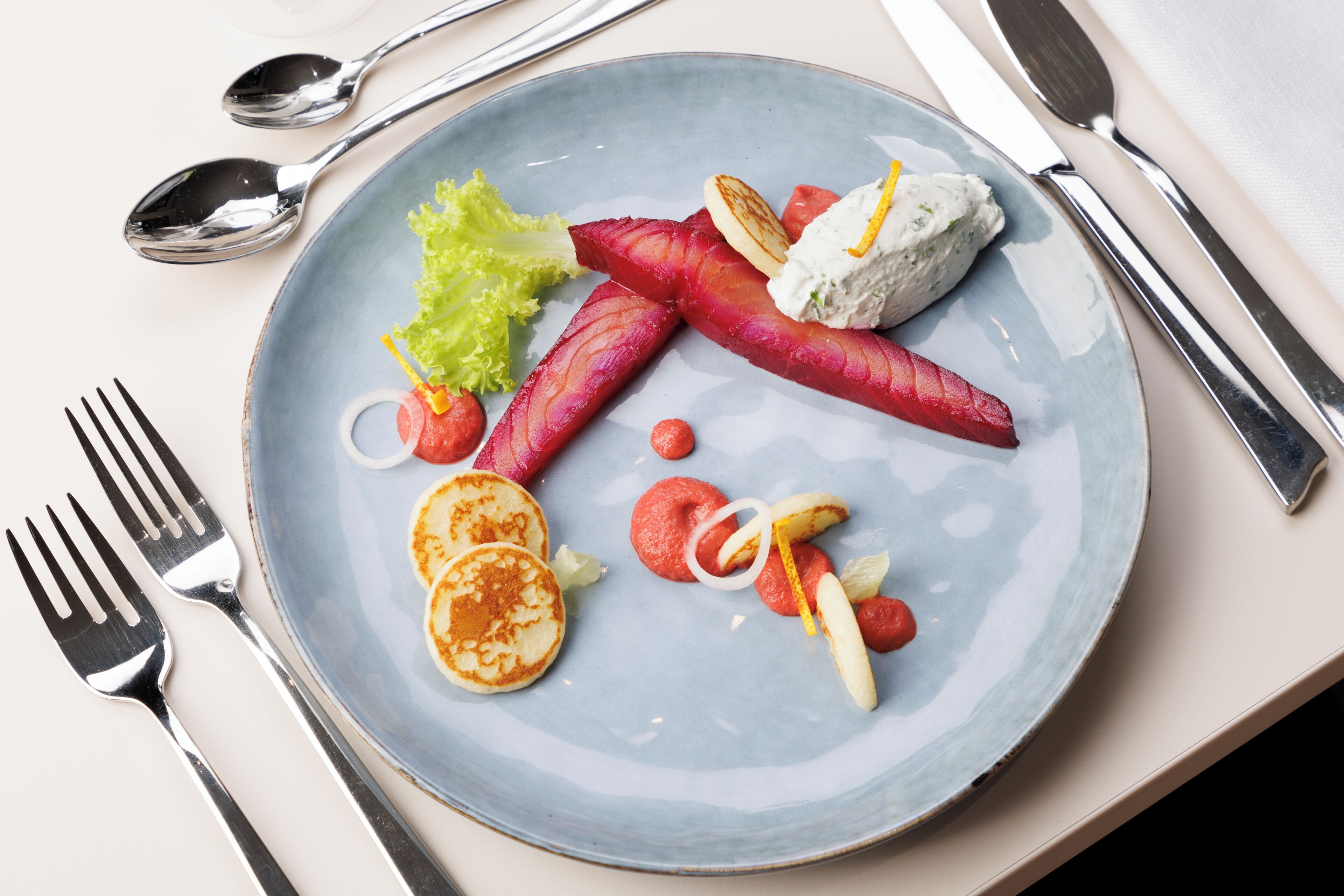 A plate with food items including pancakes, radishes, and a dollop of cream.