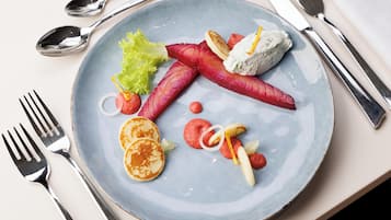 A plate with food items including pancakes, radishes, and a dollop of cream.