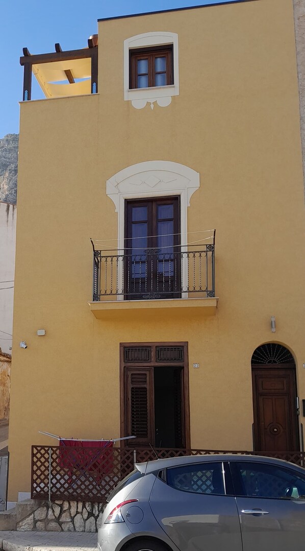 A two-story building with a balcony, a door, and a window.