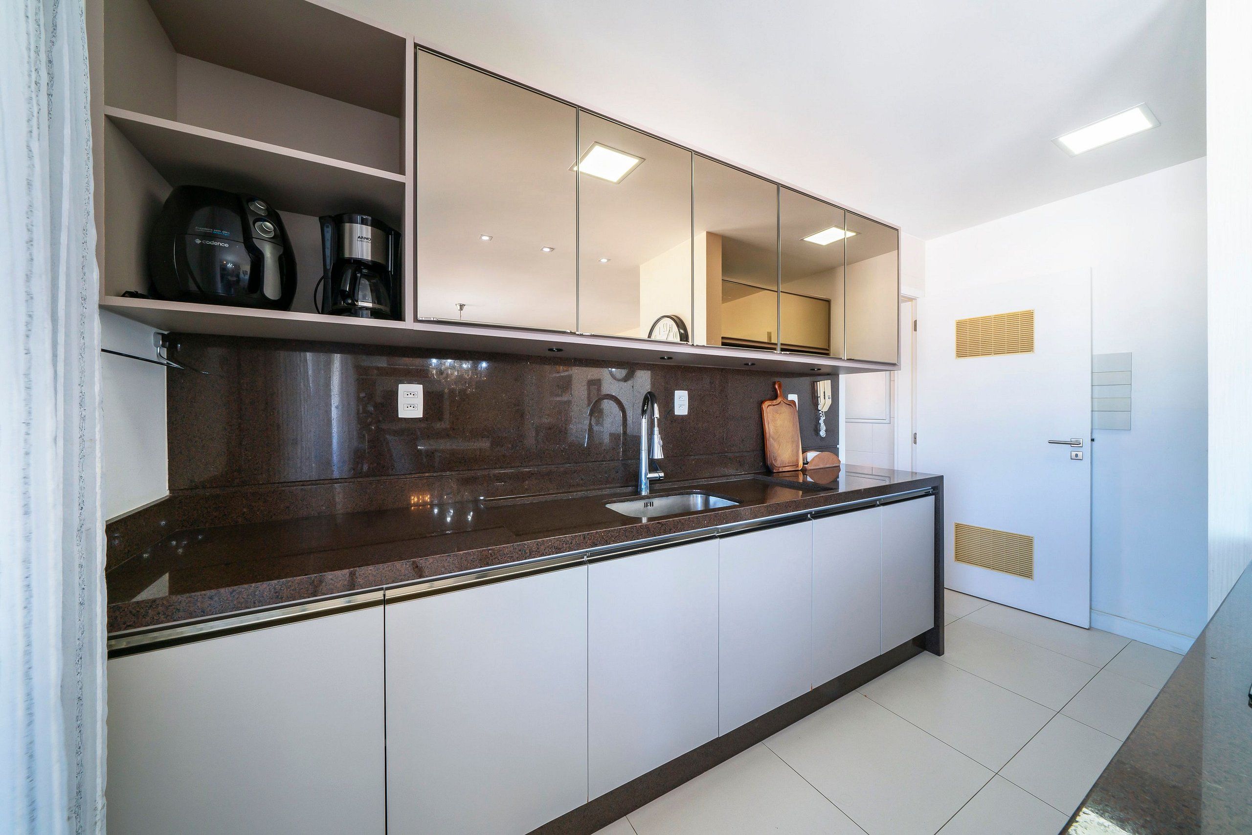 A modern kitchen with a built-in sink, a coffee maker, and a clock on the wall.