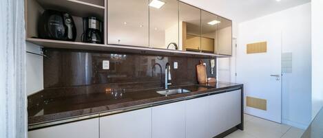A modern kitchen with a built-in sink, a coffee maker, and a clock on the wall.