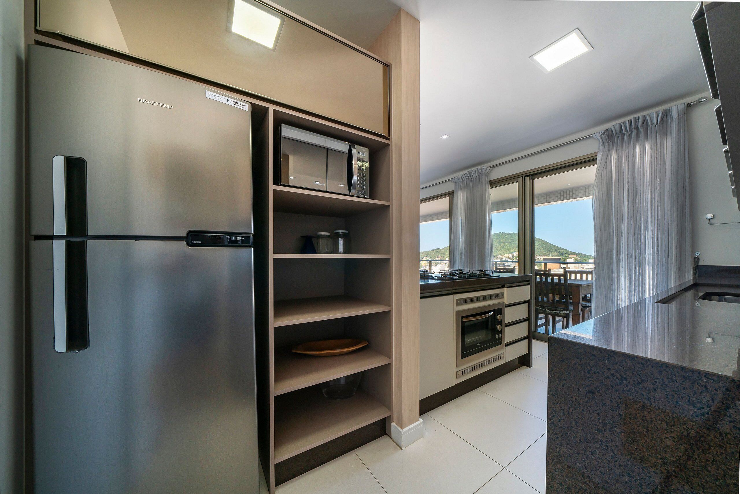 A modern kitchen with a stainless steel refrigerator, microwave, oven, and granite countertop.