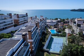 A high-rise hotel with multiple floors, a rooftop pool, and a tennis court.