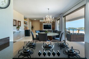 Una cocina moderna con estufa a gas, mesa de comedor, sillas y televisor montado en la pared.