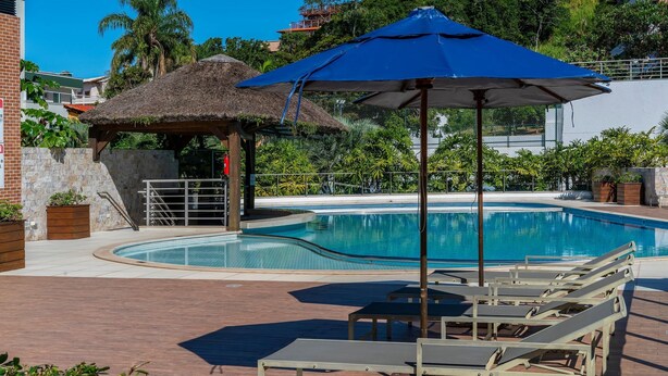 Una piscina con sillas de descanso y una estructura de techo de paja.
