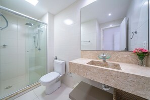 A modern bathroom with a glass-enclosed shower, a toilet, and a sink with a marble countertop.