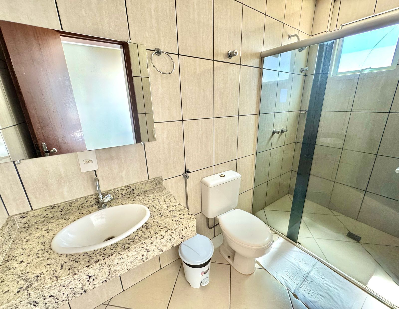 A modern bathroom with a granite countertop, a white sink, a toilet, and a glass-enclosed shower.