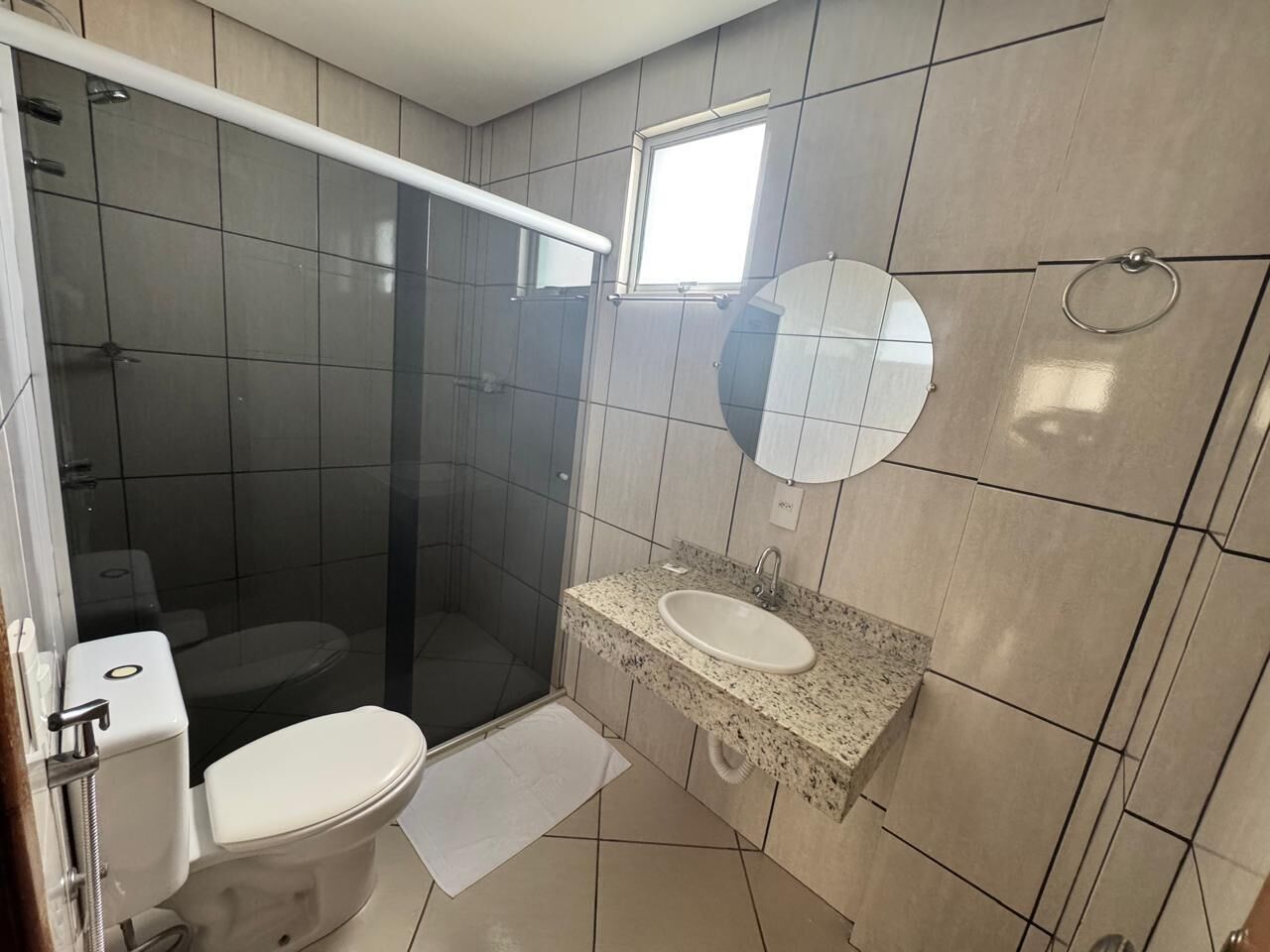Un baño con inodoro, lavamanos y ducha con mampara de vidrio.