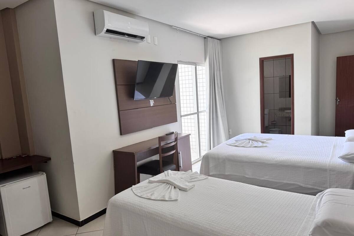 Una habitación de hotel con dos camas, televisión, aire acondicionado, escritorio y armario.