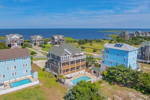 A coastal residential area with multiple houses, a swimming pool, and a view of the ocean. - SemiSoundfront Dog Friendly w/ Pool, Elevator, Hot Tub, Tiki Bar, Cmty Boat Ramp (Salvo)