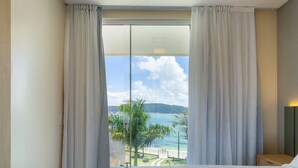 Una camera d'albergo con una grande finestra, un letto e un comodino.