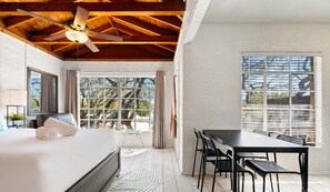 Une chambre d’hôtel moderne avec un grand lit, une table à manger avec des chaises et un ventilateur de plafond.