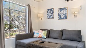A living room with a grey sofa, a glass coffee table, and two wall-mounted lamps. - LakeTravis Cozy Bungalow 6 (Volente)