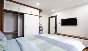 A bedroom with a bed, a wardrobe, a television, and a water dispenser. - Luxe Paradise Residence Xuan La (Hanoi)