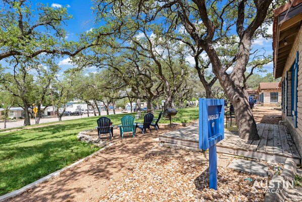 Un parque con mesas de picnic, un buzón y un edificio con contraventanas azules.
