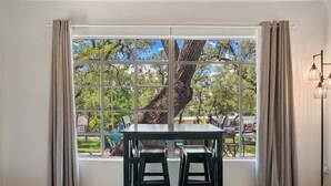 A dining area with a table and chairs, a window with curtains, and a lamp.