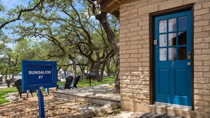 A bungalow labeled #7 with a blue door, a small porch, and outdoor seating.