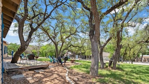 An outdoor patio area with a barbecue grill, seating, and trees.