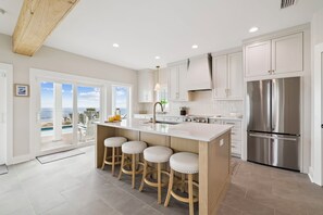 A modern kitchen with a central island, stainless steel appliances, and a view to the outside.
