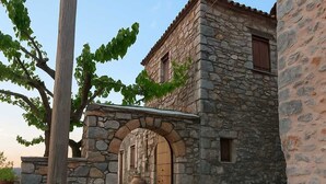 Un bâtiment en pierre doté d’une entrée en arc de cercle, d’une porte en bois et d’un chemin pavé menant à l’entrée.