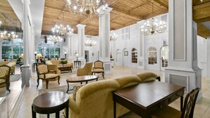 Eine großzügige Lobby mit hohen Decken, Kronleuchtern und verschiedenen Sitzgelegenheiten, darunter Sofas und Sessel.