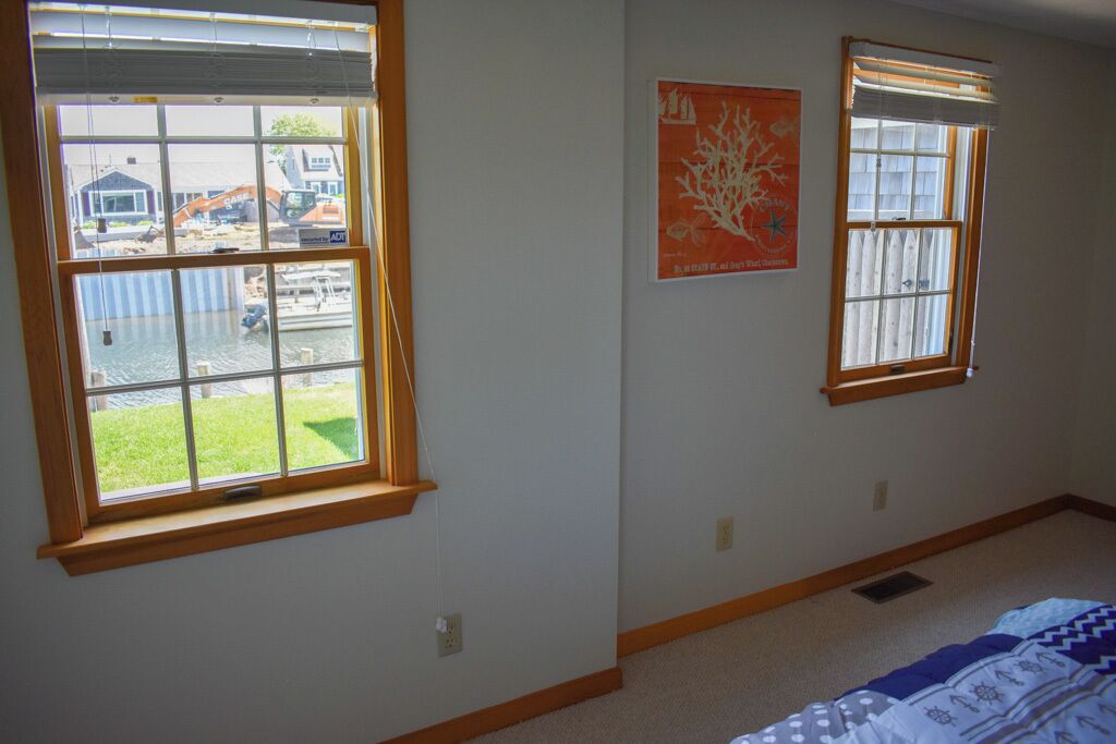 A room with two windows, a bed, and a wall-mounted poster.