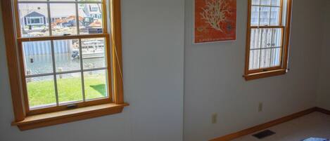 A room with two windows, a bed, and a wall-mounted poster.