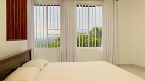 A bedroom with a bed, two windows with curtains, and a view of greenery outside. - Meridian Holiday Resort (Ratnapura)