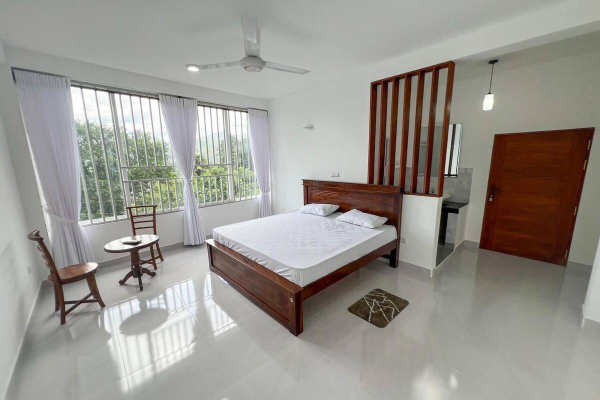 A bedroom with a large bed, a wooden chair, a small table, and a wardrobe.
