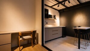 Una cocina funcional con una silla de madera, una mesita y un microondas en un estante.