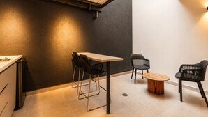 Un interior moderno con zona de comedor que incluye una mesa y sillas, una pequeña mesa redonda y una cocina con armarios.