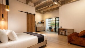 Une chambre moderne comprenant un lit, un canapé, un bureau et un coin cuisine.