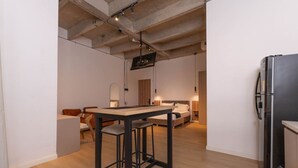 Une cuisine moderne avec un réfrigérateur noir, une table en bois et des tabourets de bar.