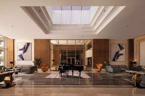 A spacious lobby with a grand piano, modern furniture, and large windows. - SRNTY Sahl Hasheesh (Sahl Hasheeh)